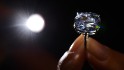 A model holds a 12.03-carat blue diamond during a press preview by auction house Sotheby's in Geneva on November 4, 2015. A 12.03-carat blue diamond could fetch a record $55 million (47 million Euros) when it goes under the hammer by Sotheby's on November 11 in Geneva. Categorised as a fancy vivid blue diamond, the Blue Moon, discovered in South Africa in January last year, is the largest cushion-shaped stone in that category to ever appear at auction. AFP PHOTO / FABRICE COFFRINI (Photo credit should read FABRICE COFFRINI/AFP/Getty Images)